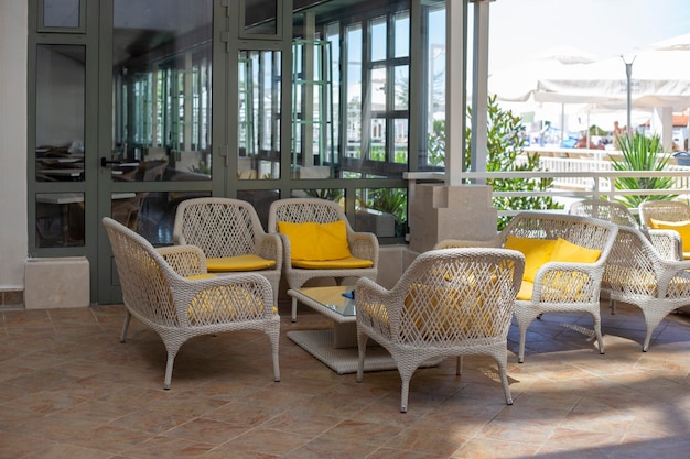 Rieten stoelen met gele kussens en tafels op het terras op zomerdag Leeg terras