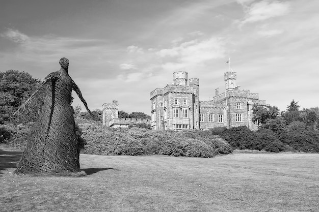 Rieten vrouw standbeeld en kasteel in Stornoway Verenigd Koninkrijk Willow sculptuur op groene gronden van Lews Castle landgoed Architectuur en design Oriëntatiepunt en attractie Zomervakantie en reislust