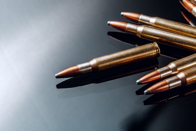 Rifle bullets or cartridges on black shiny table