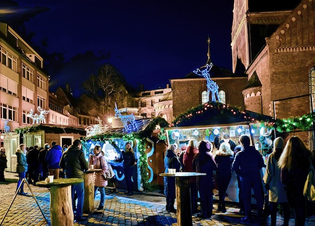 Riga, Latvia - December 24, 2015: People at Christmas market in the Dome square in center of old Riga, Latvia. At night