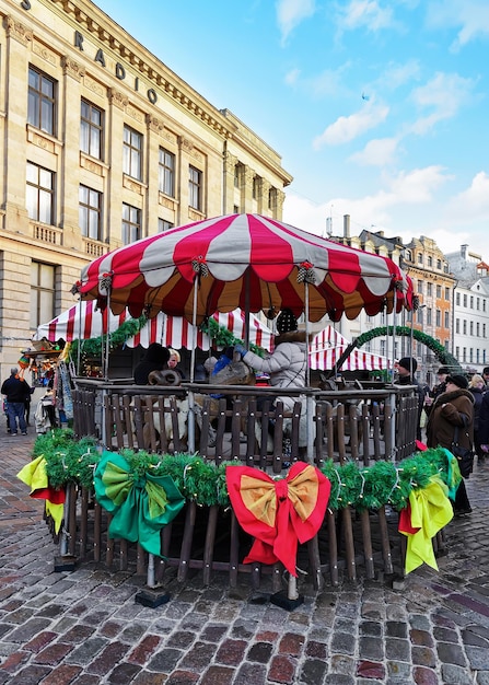 Riga, Latvia - December 25, 2015: People at carousel at Christmas market on Dome square in old Riga.