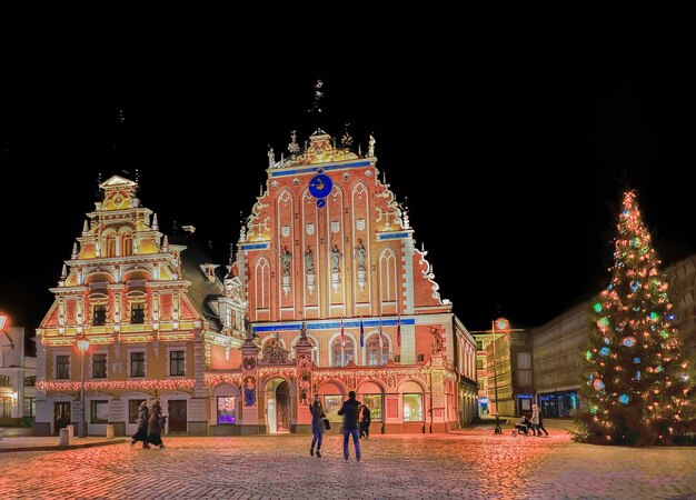 Riga, Letland - 24 december 2015: Huis van de mee-eters en de kerstboom in de buurt tijdens de kerst in Riga, Letland 's nachts