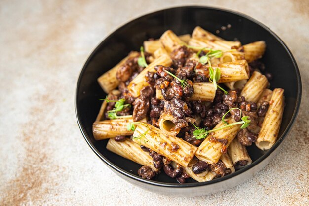 Rigatoni pasta bonen saus gezonde maaltijd eten dieet snack op tafel kopieer ruimte voedsel achtergrond