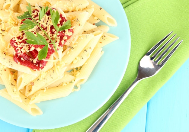 Rigatoni pasta dish with tomato sauce on blue wooden table close up