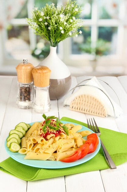 Rigatoni pasta dish with tomato sauce on white wooden table in cafe