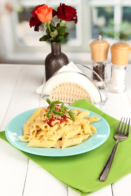 Foto piatto di pasta rigatoni con salsa di pomodoro sul tavolo di legno bianco in caffè