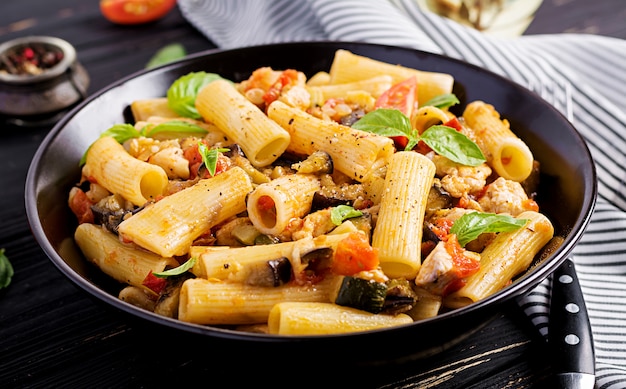 Rigatoni pasta with chicken meat, eggplant in tomato sauce in bowl.