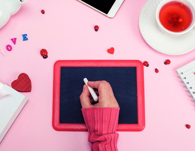 Right female hand in a pink sweater with a piece of white chalk