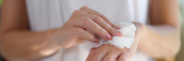 Right hand wipes left hand with piece of damp cloth closeup wet antibacterial hand wipes