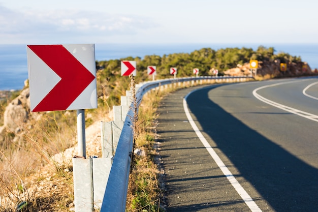 Photo right turn sign: road signs warn of a sharp turn on a narrow road.