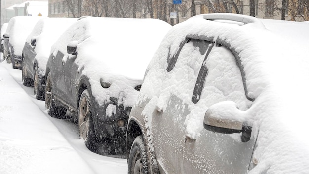 Rij auto's bedekt met sneeuw tijdens zware sneeuwstorm in de stad