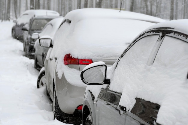 Rij geparkeerde auto's bedekt met sneeuw Besneeuwde parkeerplaats in de stadsstraat