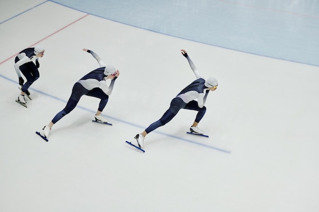 Rij jonge mannen in sportuniform en schaatsen die enkele oefeningen trainen