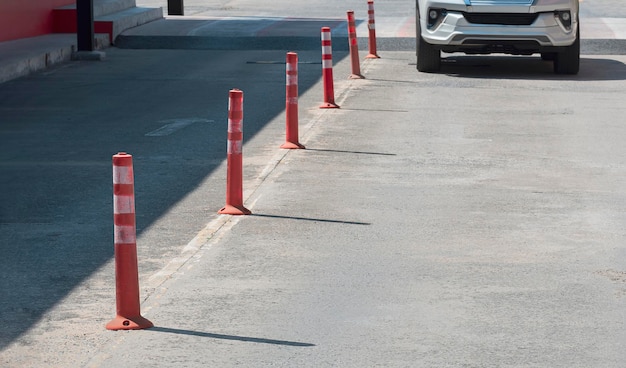 Rij oranje plastic verkeerspalen met wazige beweging van auto die langzaam naar de parkeerplaats buiten rijdt