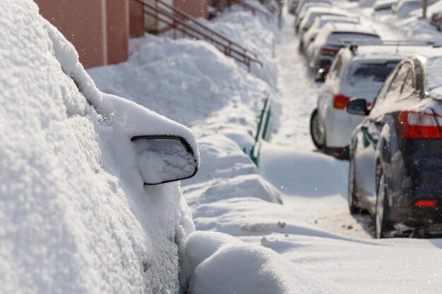 Rij sneeuw dreef auto's op een rij langs de straat in de buurt van woongebouw op winterdag sneeuwval