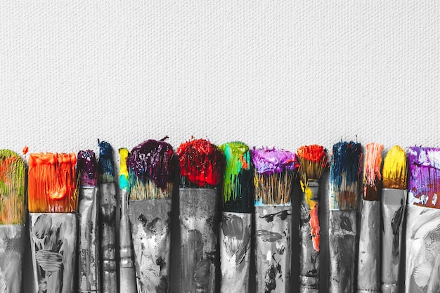 Rij van kunstenaarspenselen met kleurrijke varkenshaarclose-up op artistieke canvasachtergrond