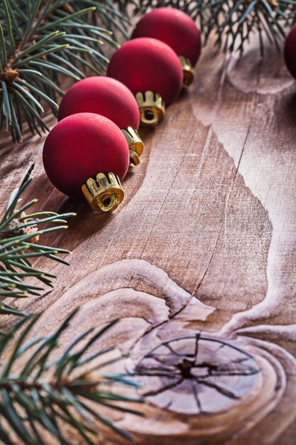 Rij van rode kerstballen takken van dennenboom op oude houten plank