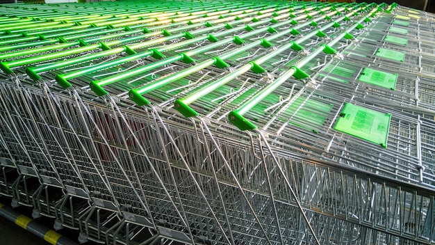 Rij winkelwagentjes met groene handvatten in supermarkt