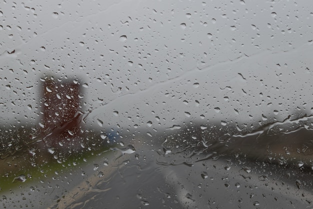 Rijden in de regen. Regendruppel op het autoglasoppervlak. Abstract verkeer in regendag. Uitzicht vanaf autostoeltje. Uitzicht op de weg door autoraam met regendruppels, selectieve aandacht.