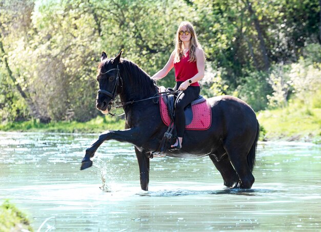 Rijdend meisje en paard in de rivier