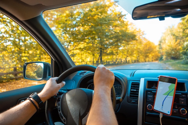 Rijdende auto herfst bos op wegkant navigatie op de telefoon