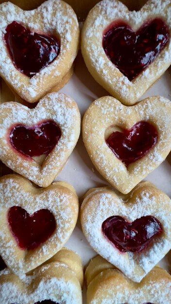 Foto rijen hartvormige koekjes gevuld met aardbeienjam in een bakkerijdoos