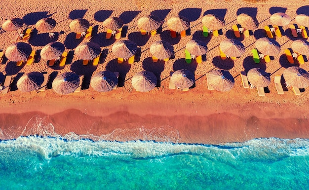 Rijen stroparasols op het zandstrand tropisch strandlandschap met parasols bovenaanzicht van het zeegezicht