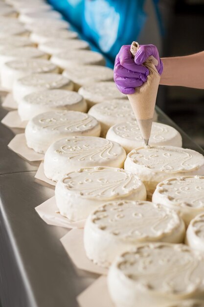 Rijen witte taarten Werknemers versieren met de hand witte taarten Een zoet meesterwerk creëren Prachtig handgemaakt ornament