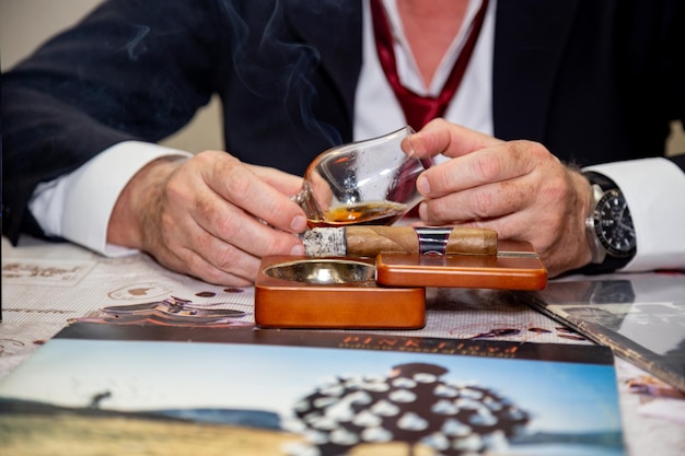 Rijke blanke man in een pak en stropdas met sigaar en whisky relaxmoment