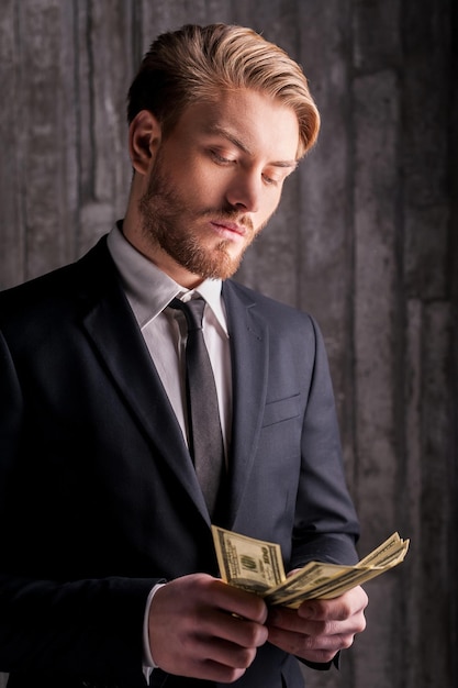 Rijke knap. knappe jonge man in formalwear die geld telt