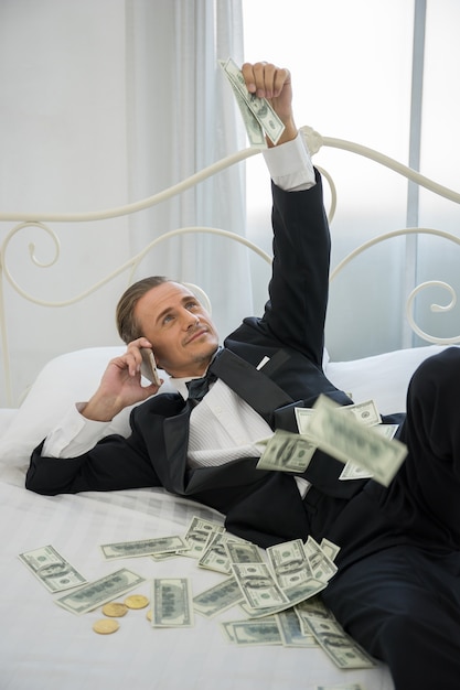 Rijke man liggend op het bed met dollar biljetten. Succes bedrijfsconcept.