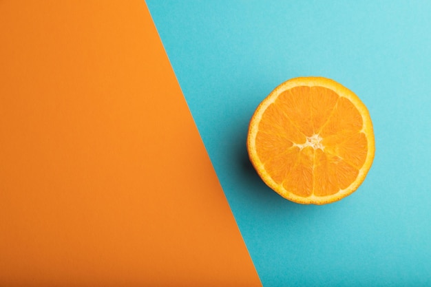 Rijp gesneden sinaasappel op oranje en blauwe pastelachtergrond Bovenaanzicht kopie ruimte