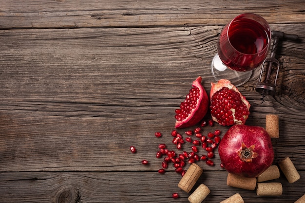 Rijp granaatappelfruit met een glas wijn en een kurketrekker op een houten achtergrond