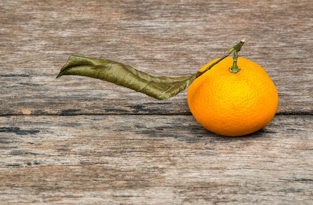 Rijp oranje fruit en droog blad op houten