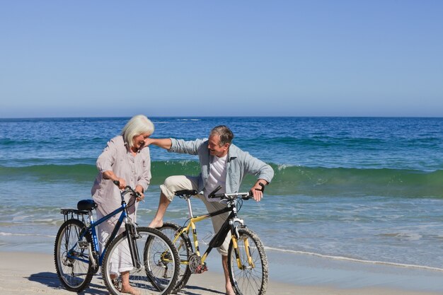 Rijp paar met hun fietsen op het strand