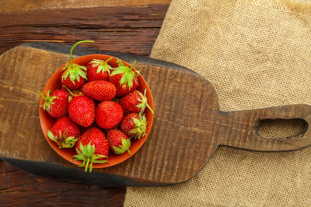 Rijpe aardbeien in een bord op een houten tafel op een houten bord.