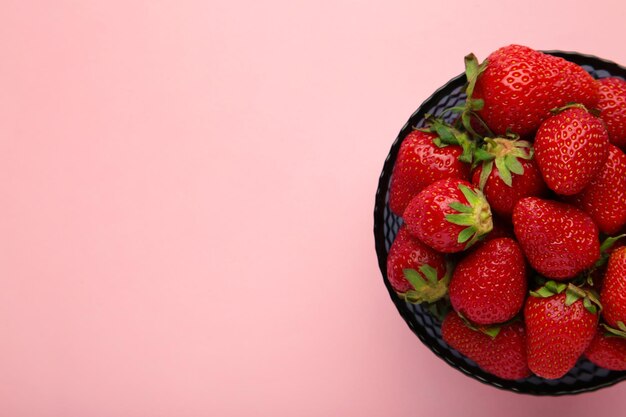 Rijpe aardbeien in kom op roze achtergrond Ruimte voor tekst