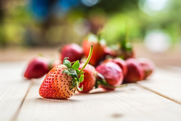 Rijpe aardbeien op houten lijst met vage aardachtergrond