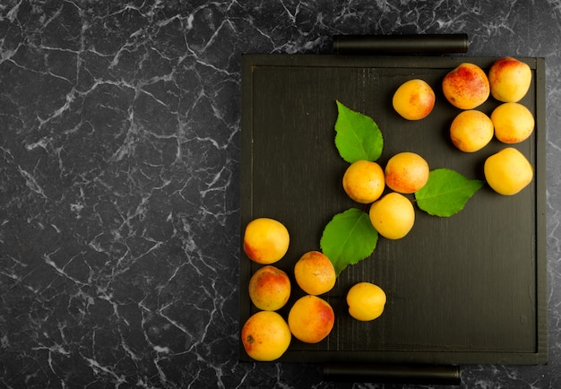 Rijpe abrikozen die op een zwart dienblad liggen
