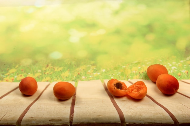 Rijpe abrikozen op een houten bord, groene zomerachtergrond, plaats voor tekst
