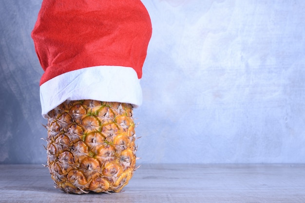 Rijpe ananas, ananas met zonnebril in kerstmuts. Nieuwjaar fruit concept