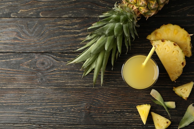 Rijpe ananas en glas sap op houten achtergrond