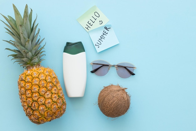 Rijpe ananas-kokoszonnebril en fles room op een blauwe achtergrond hallo zomerconcept