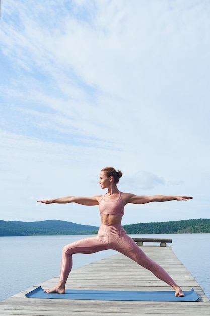 Rijpe atletische vrouw die yoga beoefent tegen de achtergrond van een prachtig zeegezicht Gezond levensstijlconcept