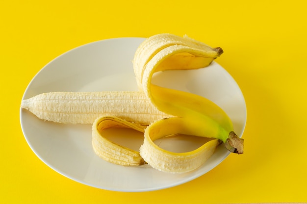 Rijpe banaan op zwarte plaat op gele achtergrond. Tropisch fruit om te eten.