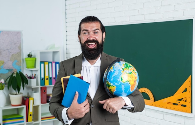 Rijpe bebaarde geograaf met baard en snor draagt een pak in het klaslokaal op school