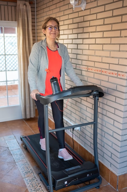 Foto rijpe blanke vrouw die op een gymnastiekmachine loopt om in vorm te blijven en te sporten