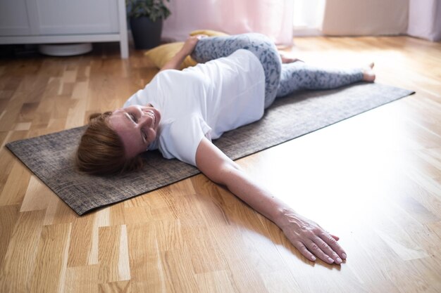 Rijpe blanke vrouw doet yoga pose training thuis