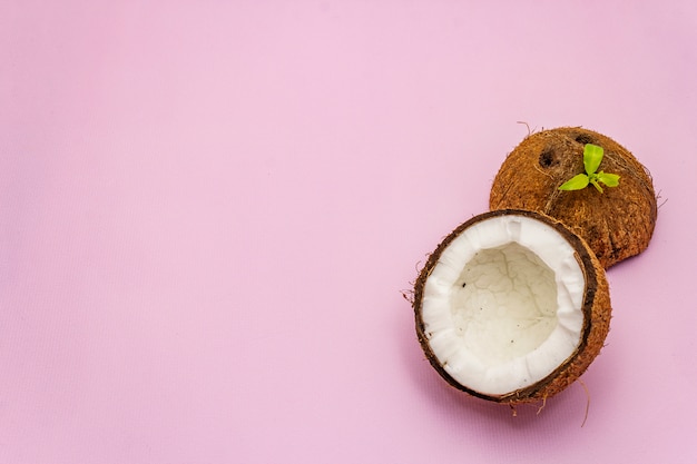 Rijpe die kokosnoot op twee half wordt geïsoleerd op roze achtergrond wordt gesneden