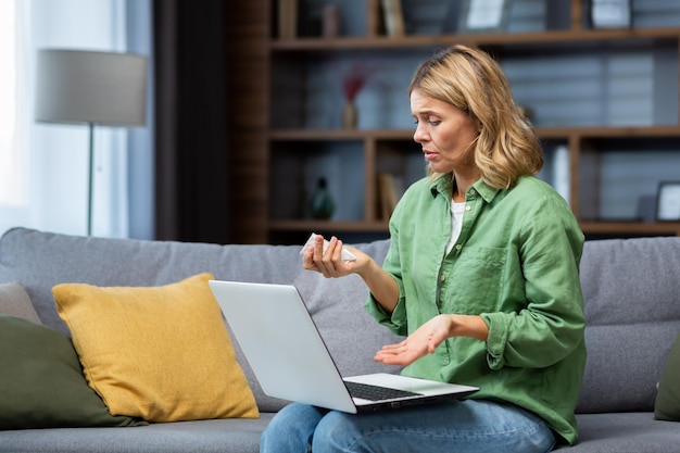 Foto rijpe eenzame vrouw alleen thuis huilend in depressie pratend op videogesprek met psycholoog